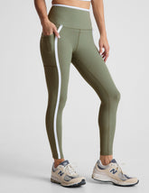 green high-waisted midi length legging with side pockets and white piping.